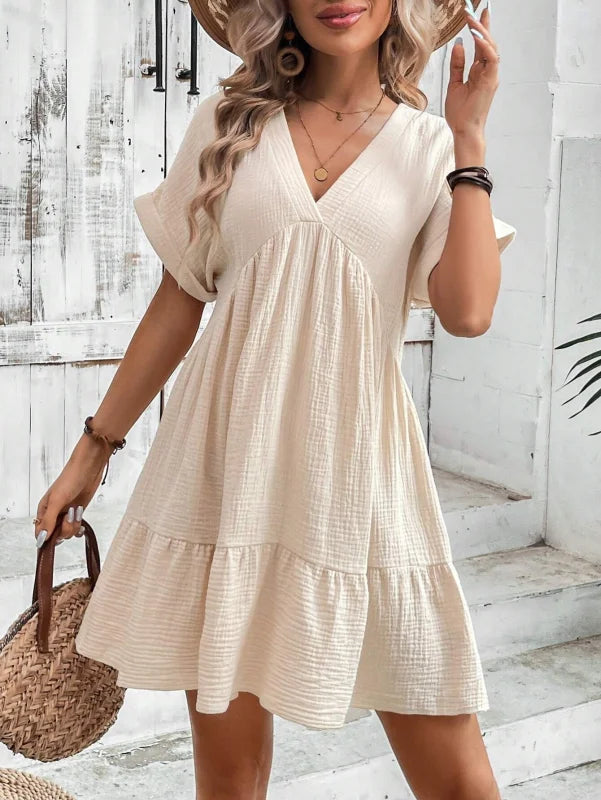 Flowy V-neck mini dress with pleated skirt in soft cotton-poly blend, perfect for everyday wear or casual occasions.