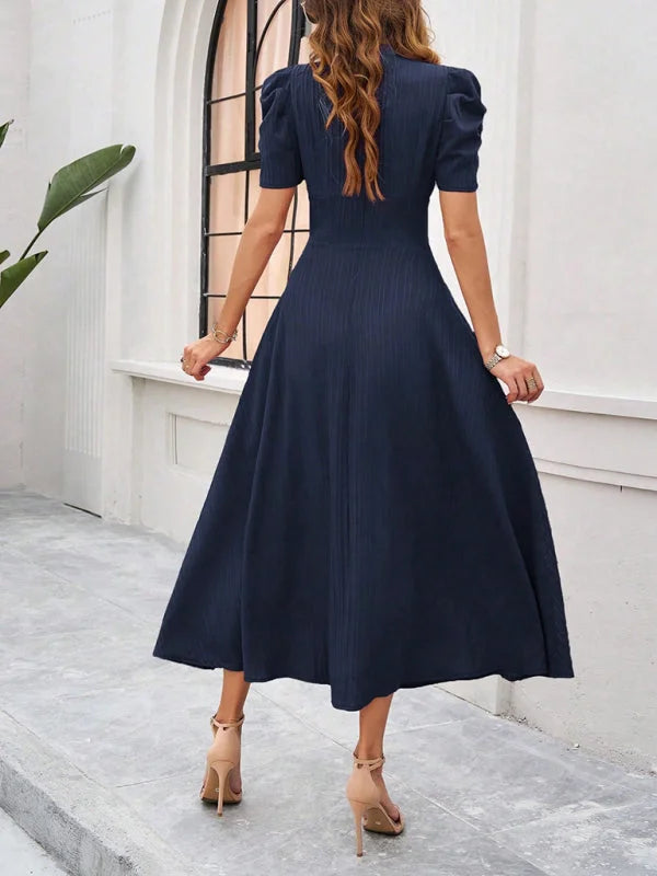 Navy blue midi dress with ruched waist and V-neck design made of soft jersey fabric.