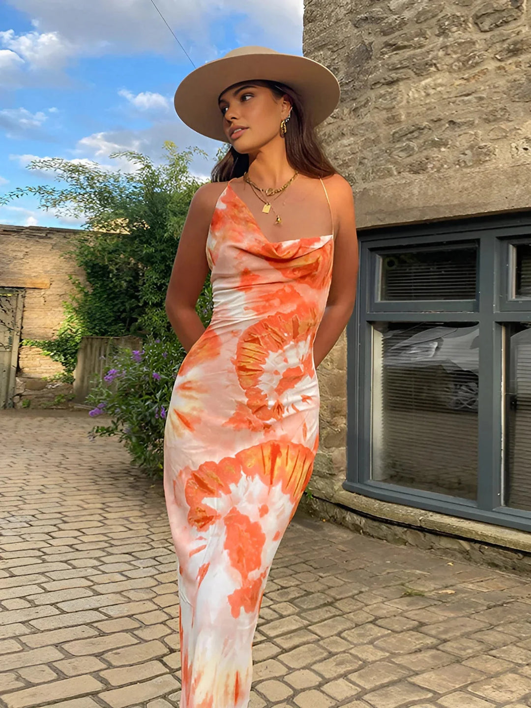 Orange floral dress with a sleeveless design, in a floor-length cut. The dress features a vibrant floral pattern on a…