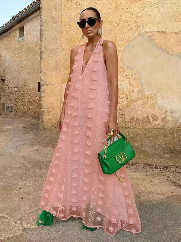 Pink halter neck maxi dress with floral embellishments. Flowy and elegant design perfect for a summer garden party.