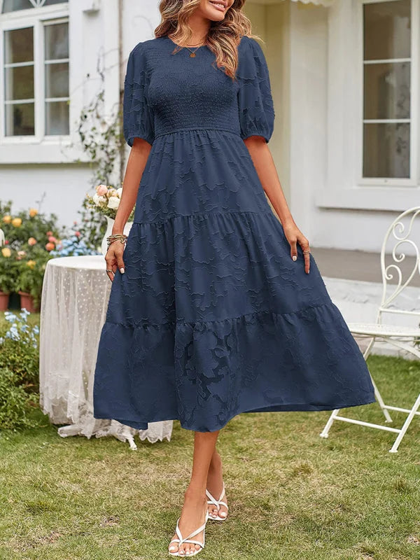 Dark blue tiered midi dress with textured detail, crafted from lightweight fabric. Perfect for casual or formal occasions.