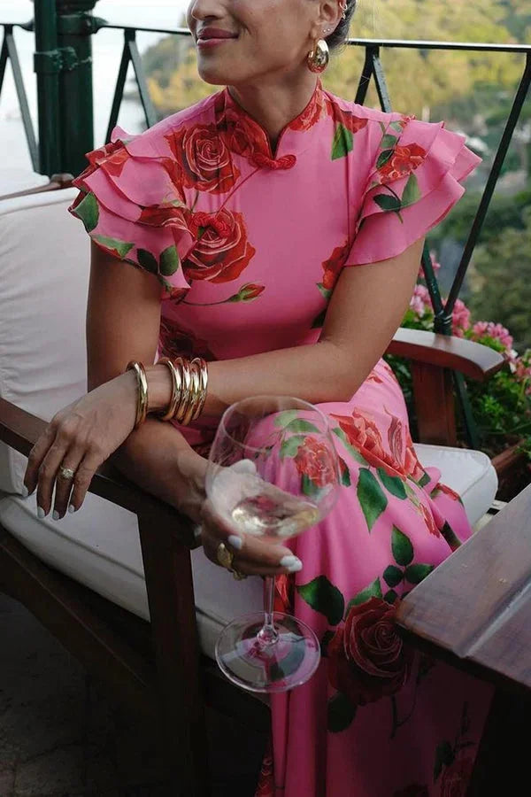 Pink maxi dress featuring a floral print, high neckline, and ruffled sleeves in a soft and lightweight fabric.