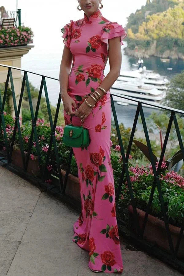 Pink maxi dress featuring a floral print, high neckline, and ruffled sleeves. Perfect for a feminine and chic look.