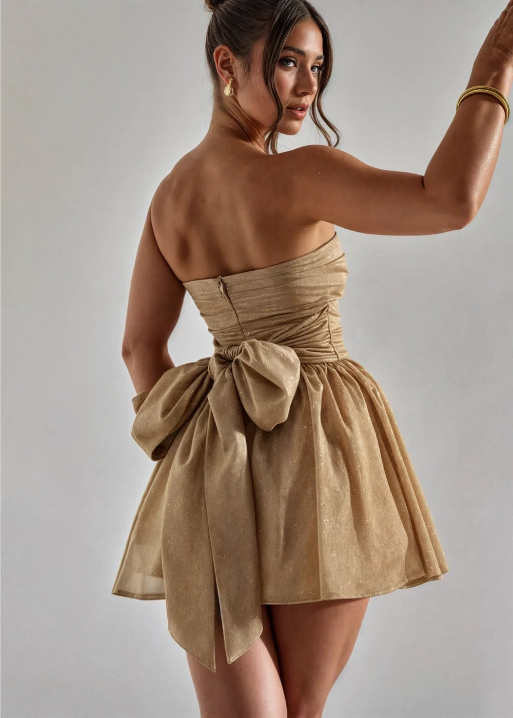 Golden strapless mini dress with bow detail, perfect for a special occasion, made from a silky and elegant fabric.