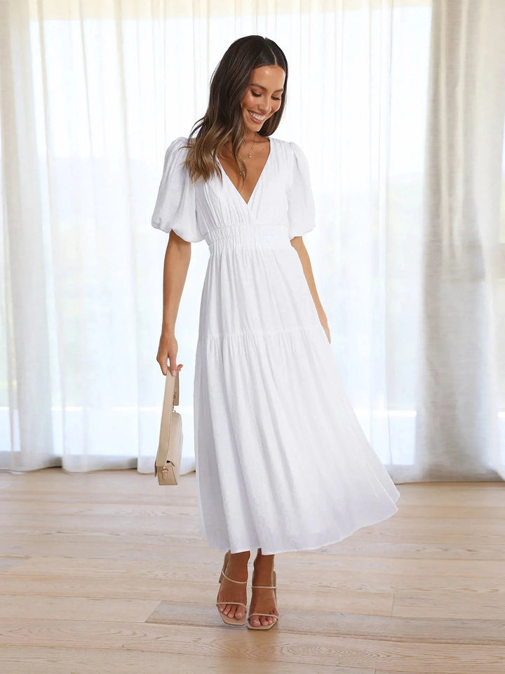 White flowy dress with puff sleeves, elastic waist for a comfortable fit. Features a relaxed silhouette in a lightweight…
