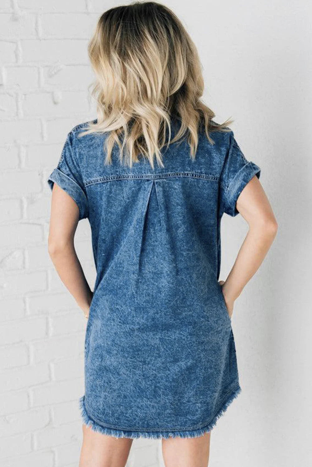 Blue denim button-up mini dress with frayed hem. Casual chic style for everyday wear, perfect for a relaxed weekend outing.