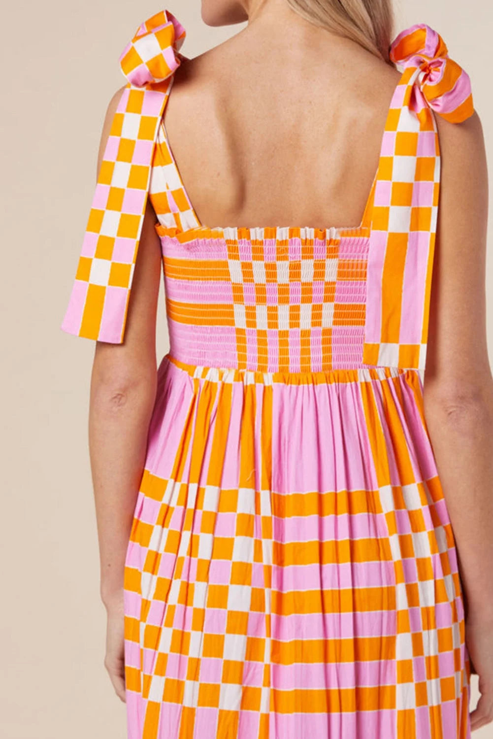 Pink orange gingham smocked maxi dress made of lightweight cotton with a flattering silhouette and elegant detailing.