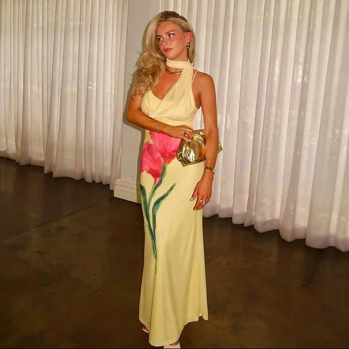 Yellow floral maxi dress with halter top for women; made of flowy fabric, featuring a vibrant floral print perfect for…