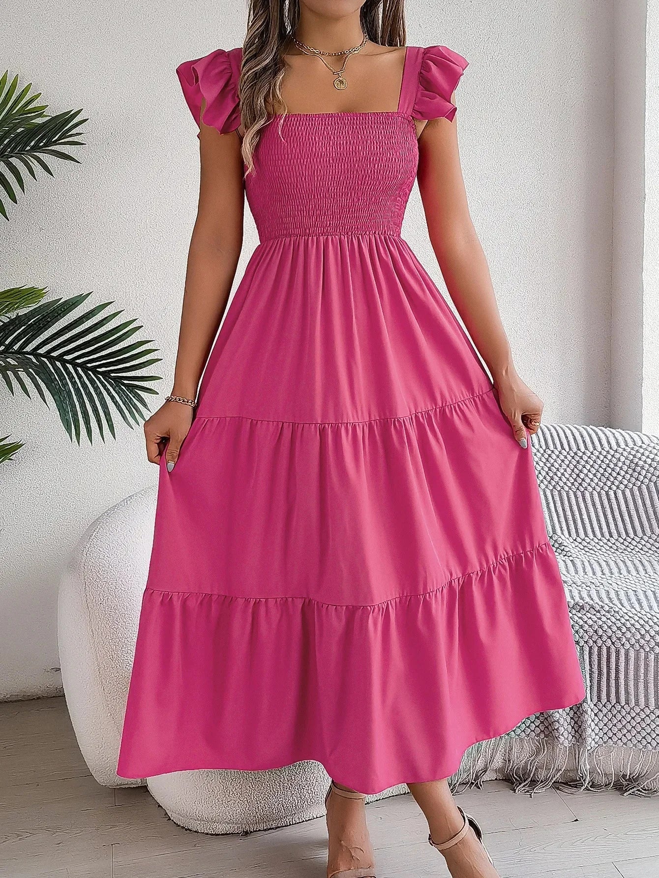 Pink tiered ruffle smocked midi dress, made from lightweight fabric. Features a charming design with subtle detailing.