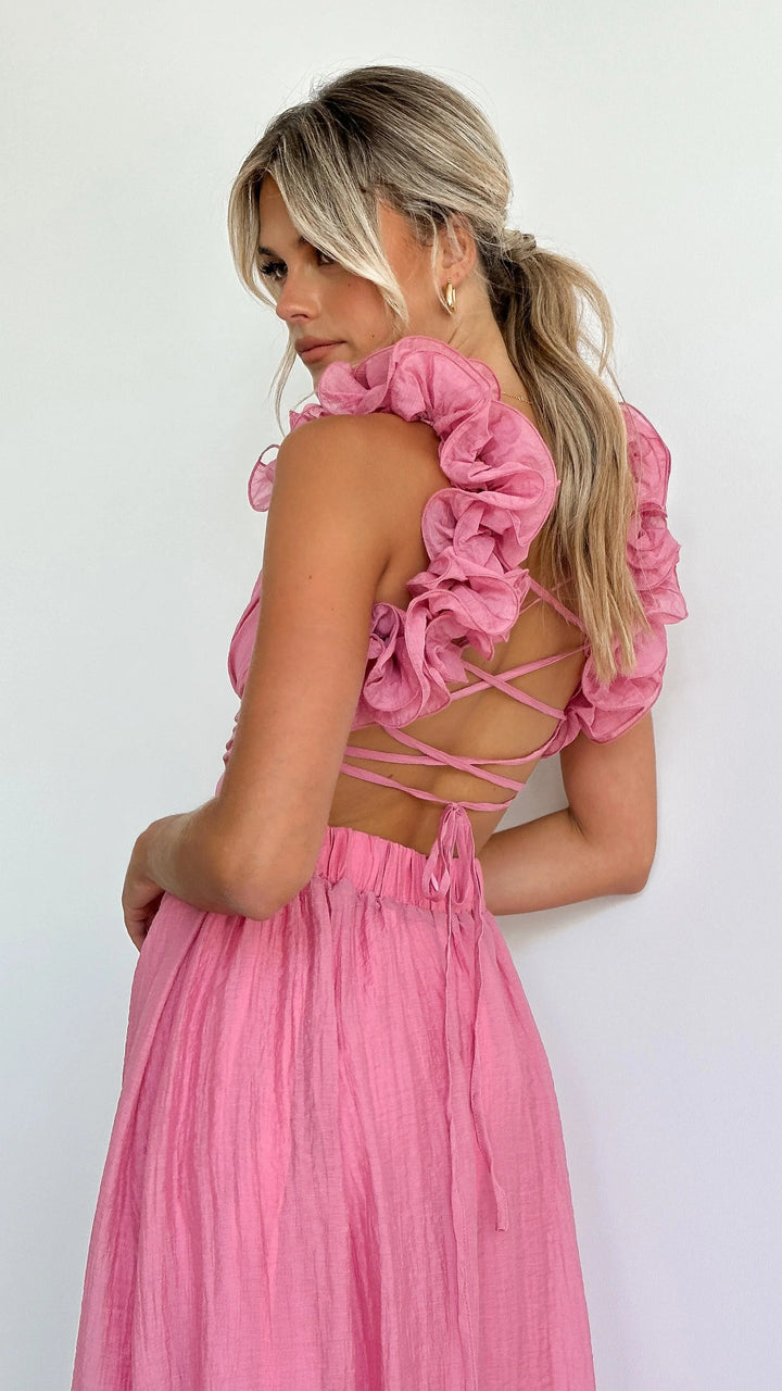 Pink midi dress with twisted bust detail, featuring delicate shoulder ruffles. Perfect for a stylish and elegant look.