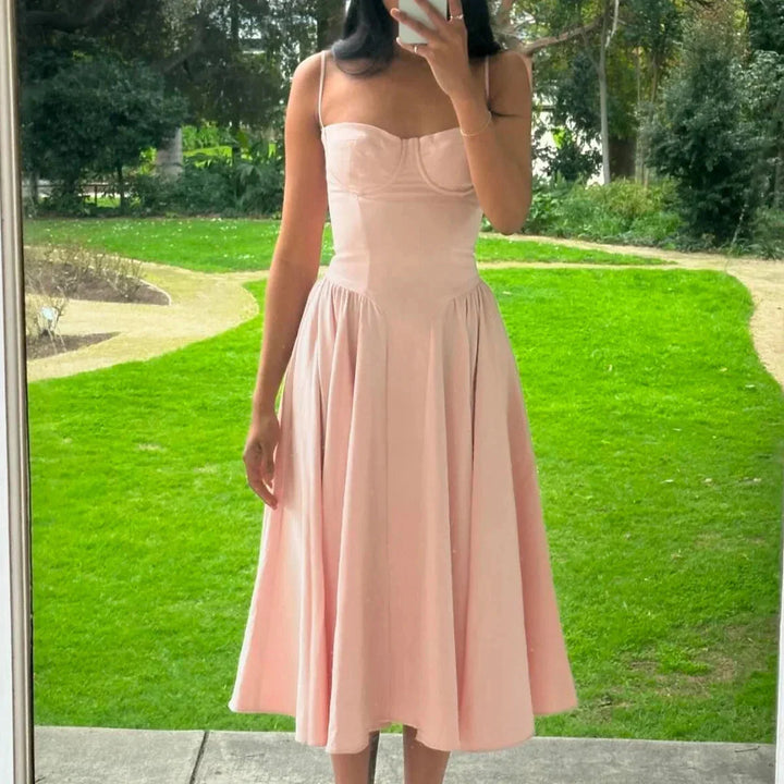 Pink mid-length bustier dress with a pleated skirt made from soft polyester fabric. Features a fitted bodice and a flowy…