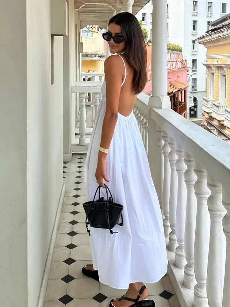 White midi dress with a sleek open-back design, made from soft and flowing fabric. Perfect for a refined and elegant look.