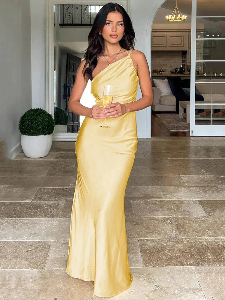 Yellow satin maxi dress with one-shoulder design, flowing silhouette, perfect for summer events and parties.