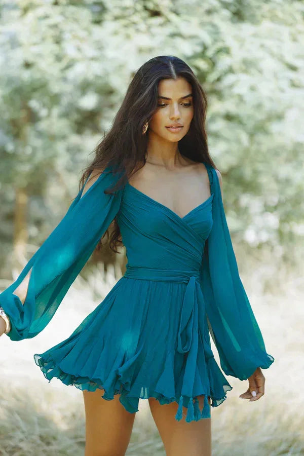 Dark teal draped mini dress with ruffled hem, elegantly designed for a sophisticated look. The dress features a unique…