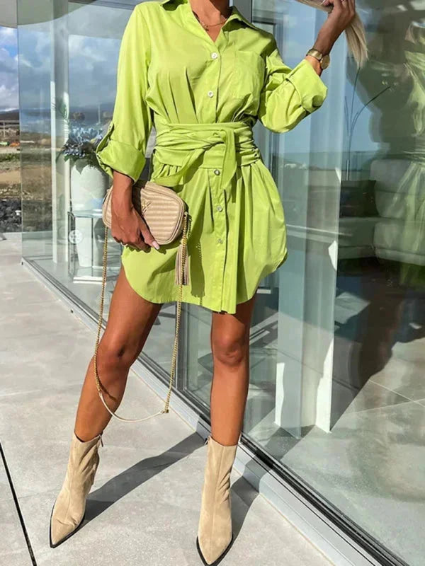 "Short shirt dress in neutral tone with belted waist and rolled sleeves, ideal for casual and formal occasions."