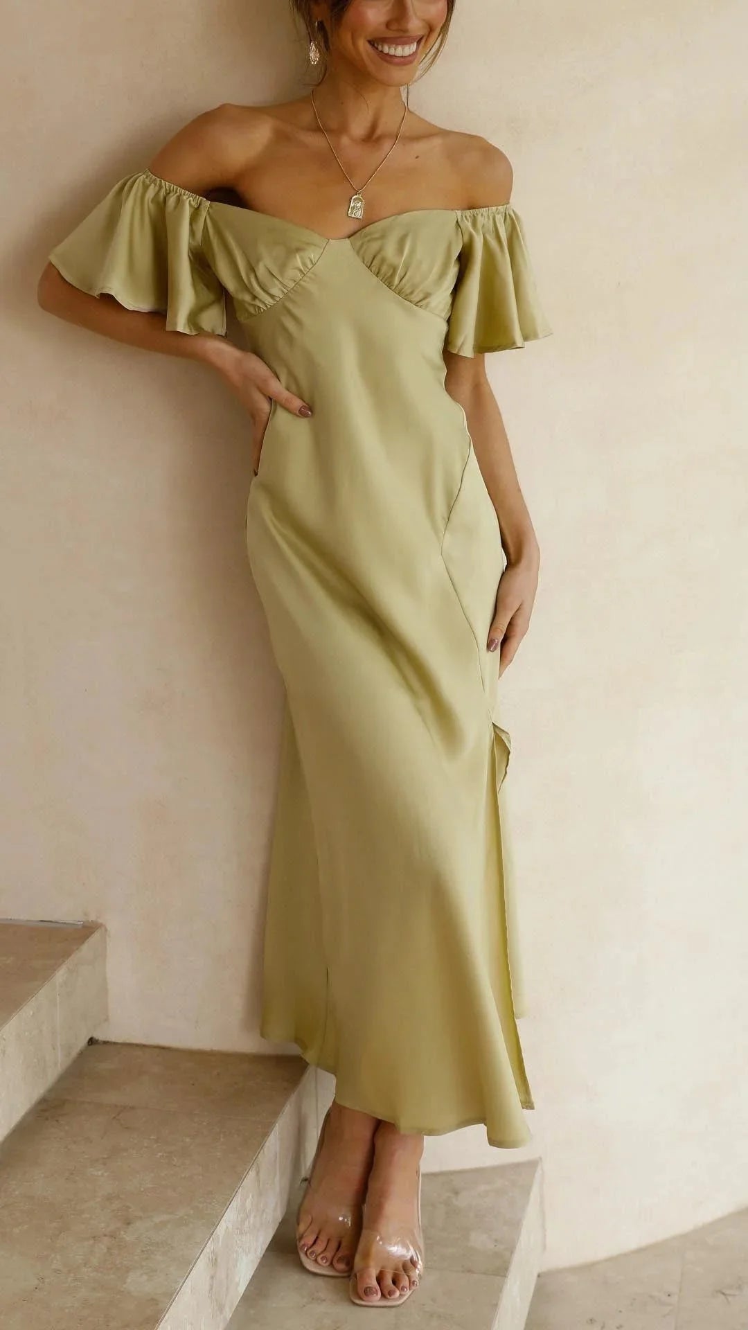 "Off-shoulder maxi dress with slits, perfect for summer days. Flowy fabric, elegant design, white, worn by model standing on…