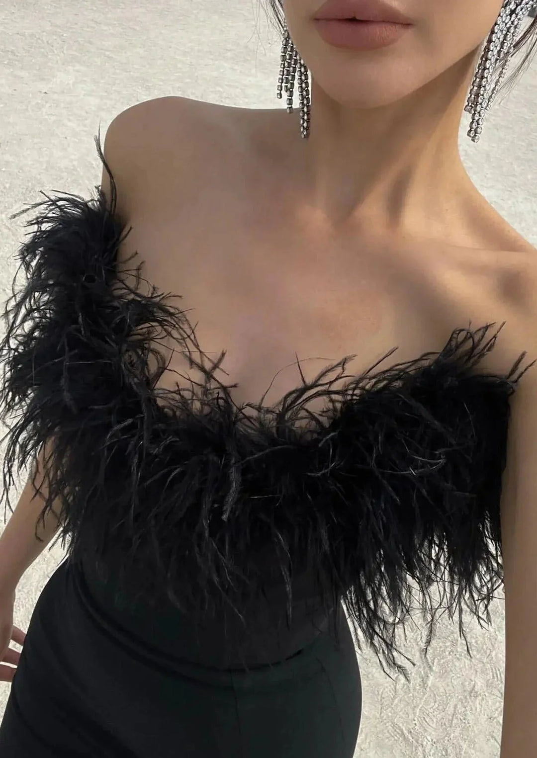 Strapless black maxi dress with feather details, perfect for a rebel-chic look.