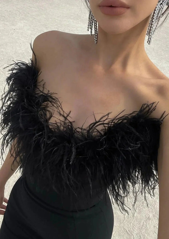 Strapless black maxi dress with feather details, perfect for a rebel-chic look.