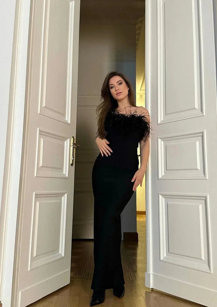 Black strapless maxi dress with feather detailing, perfect for a chic and elegant look at any event.