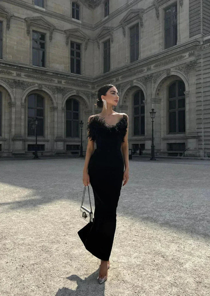 Sleek black strapless maxi dress with feather details, perfect for strong and stylish women.